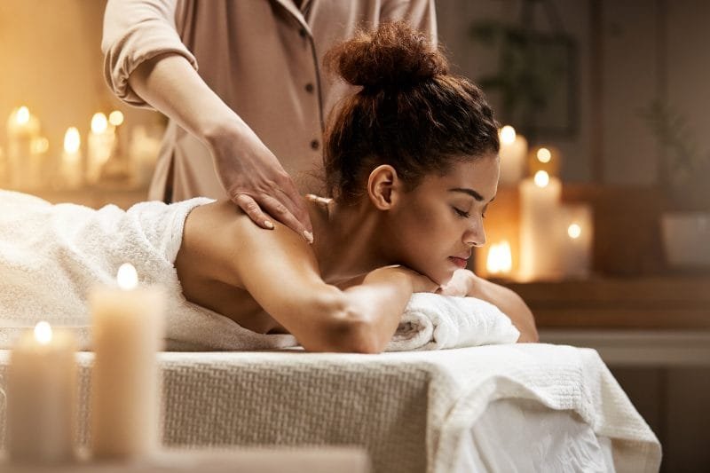 Young tender african girl smiling enjoying massage with closed eyes in a private villa.